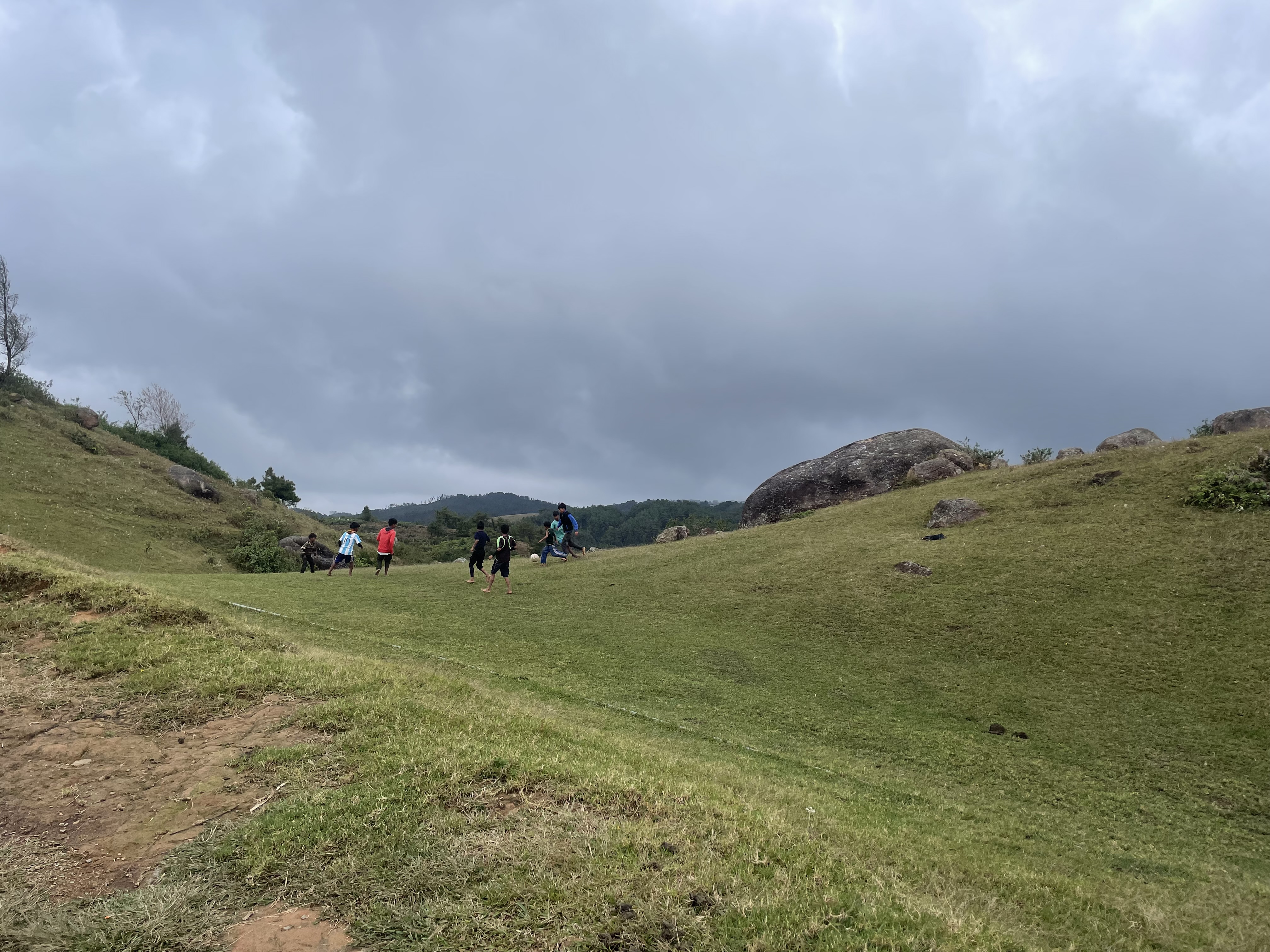 Kids playing football on the side of a small hill